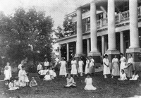 Photo of orphanage with children in front, standing and sitting on the lawn
