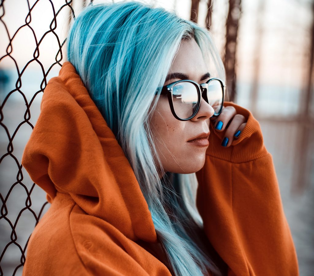 Photo of a young woman with glasses and blue hair.