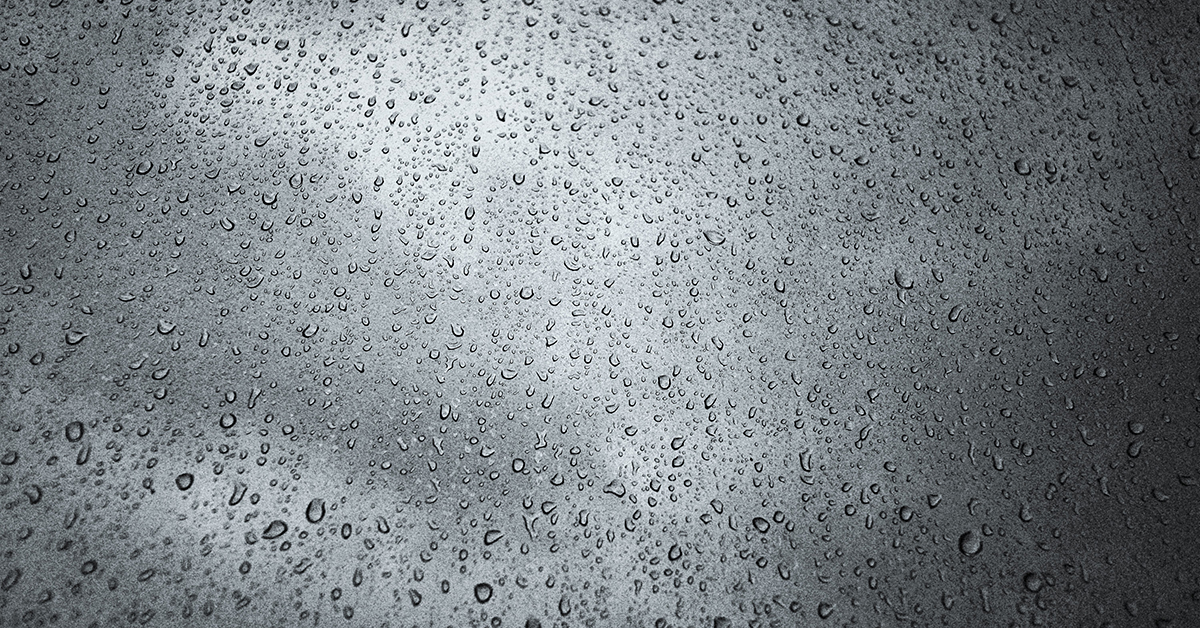 Photo of raindrops on glass against a cloudy sky