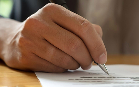 Photo of a someone signing a document.