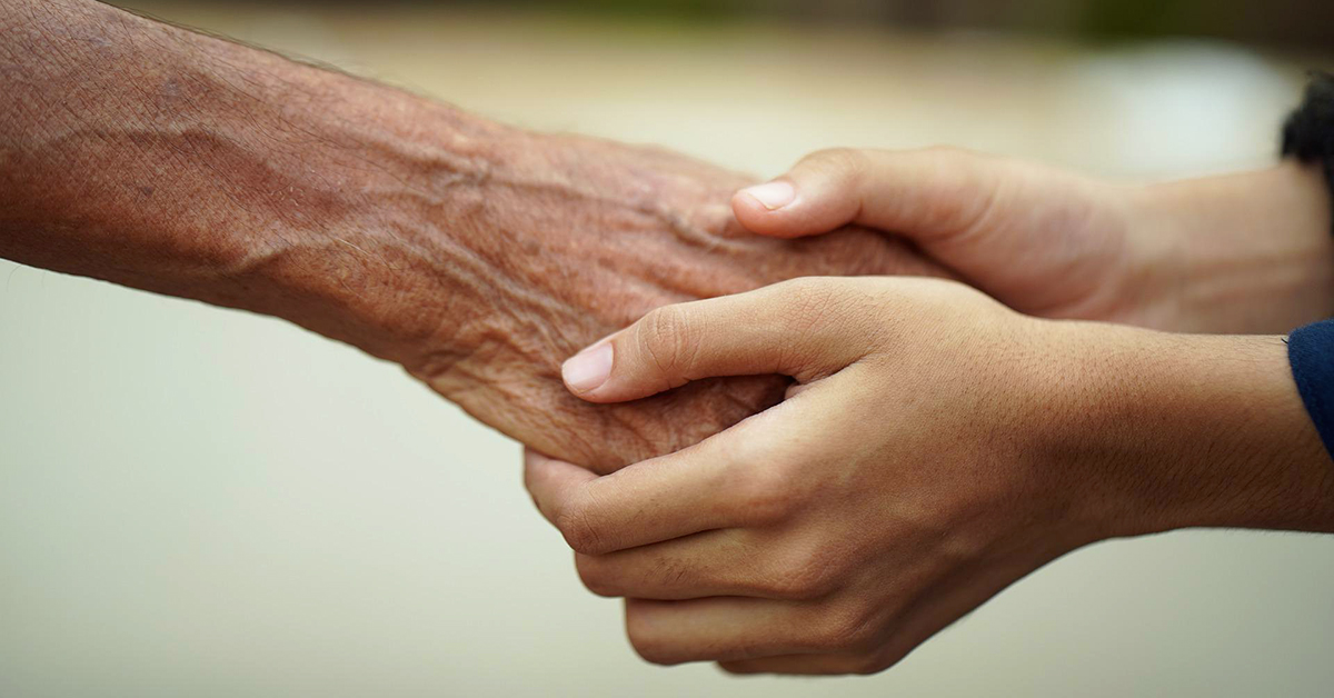 Photo of two hands grasping another person's hand.